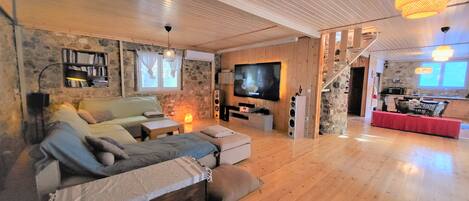 A cozy living room with a sofa, TV, and a staircase leading to a kitchen.