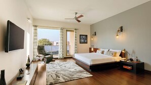 Un dormitorio moderno con una cama grande, un televisor de pantalla plana, un ventilador de techo y vistas al exterior.