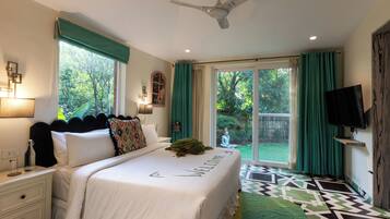 A bedroom with a bed, a ceiling fan, a TV, and a view of the outdoors.