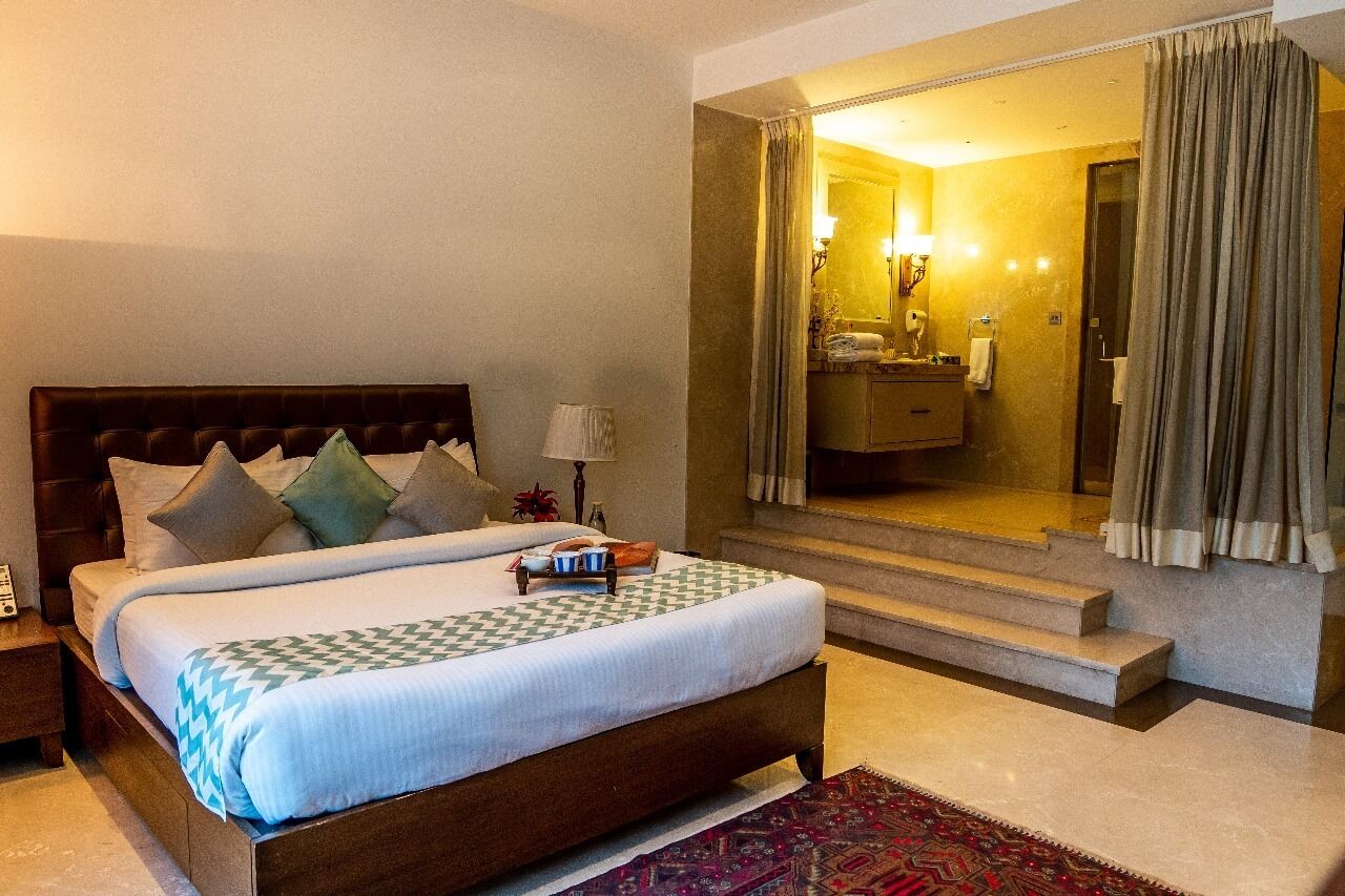 A hotel room with a large bed, a bathroom mirror, and a view of the bathroom.