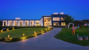 Un edificio moderno con un camino bien iluminado y una zona ajardinada.