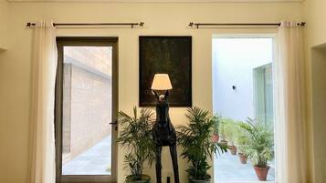 A room with a large window, a lamp, and potted plants.
