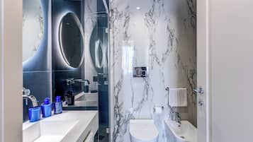 A modern bathroom with a large mirror, a white sink, a toilet, and a bathtub.