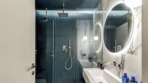 A modern bathroom with a glass-enclosed shower, a white sink, and a large mirror with a circular frame. - Sospeso Boutique Hotel (Milan)