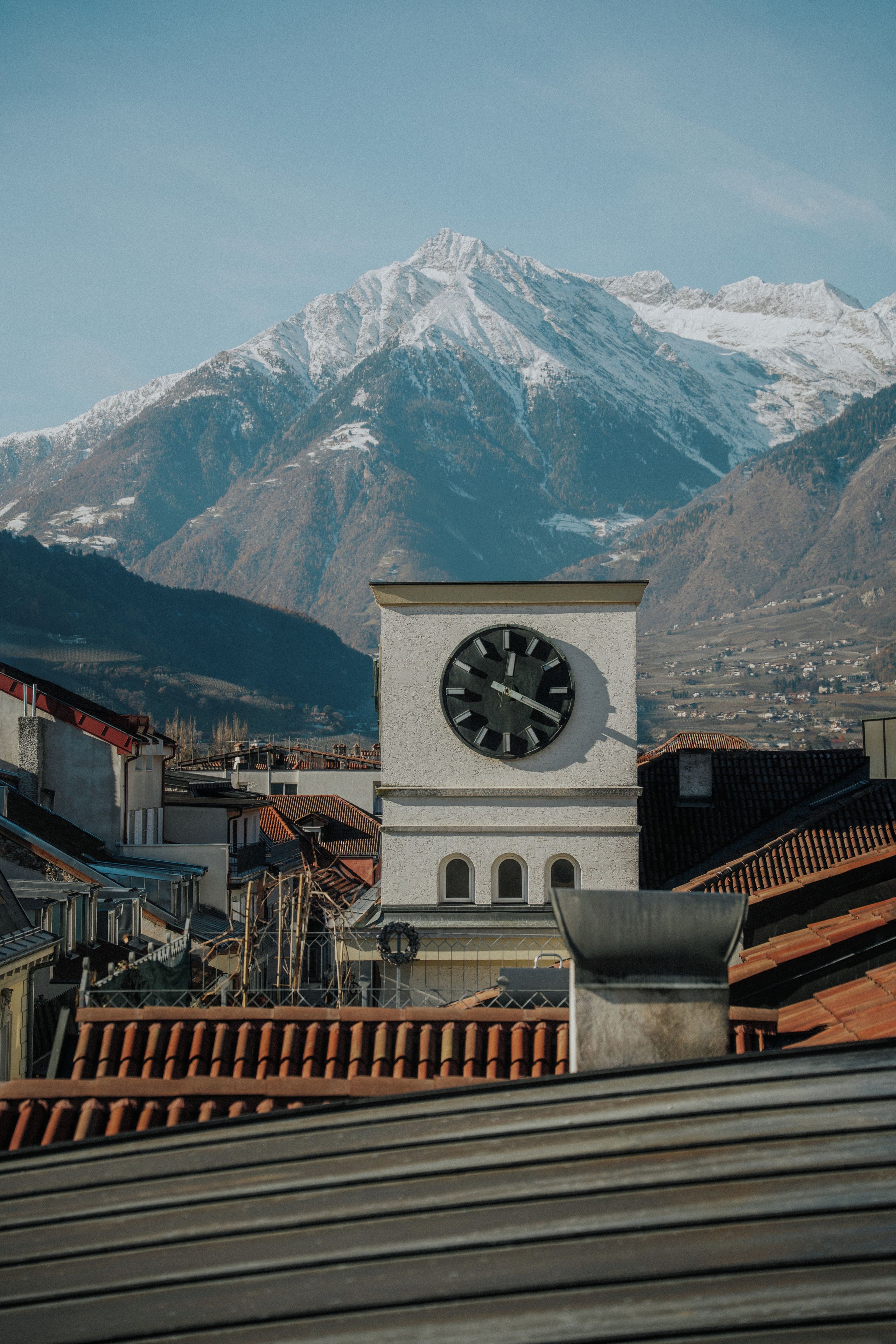 Um campanário com vista para montanhas cobertas de neve ao fundo.