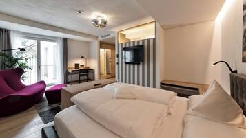 A modern hotel room with a large bed, a desk, a chair, and a TV.
