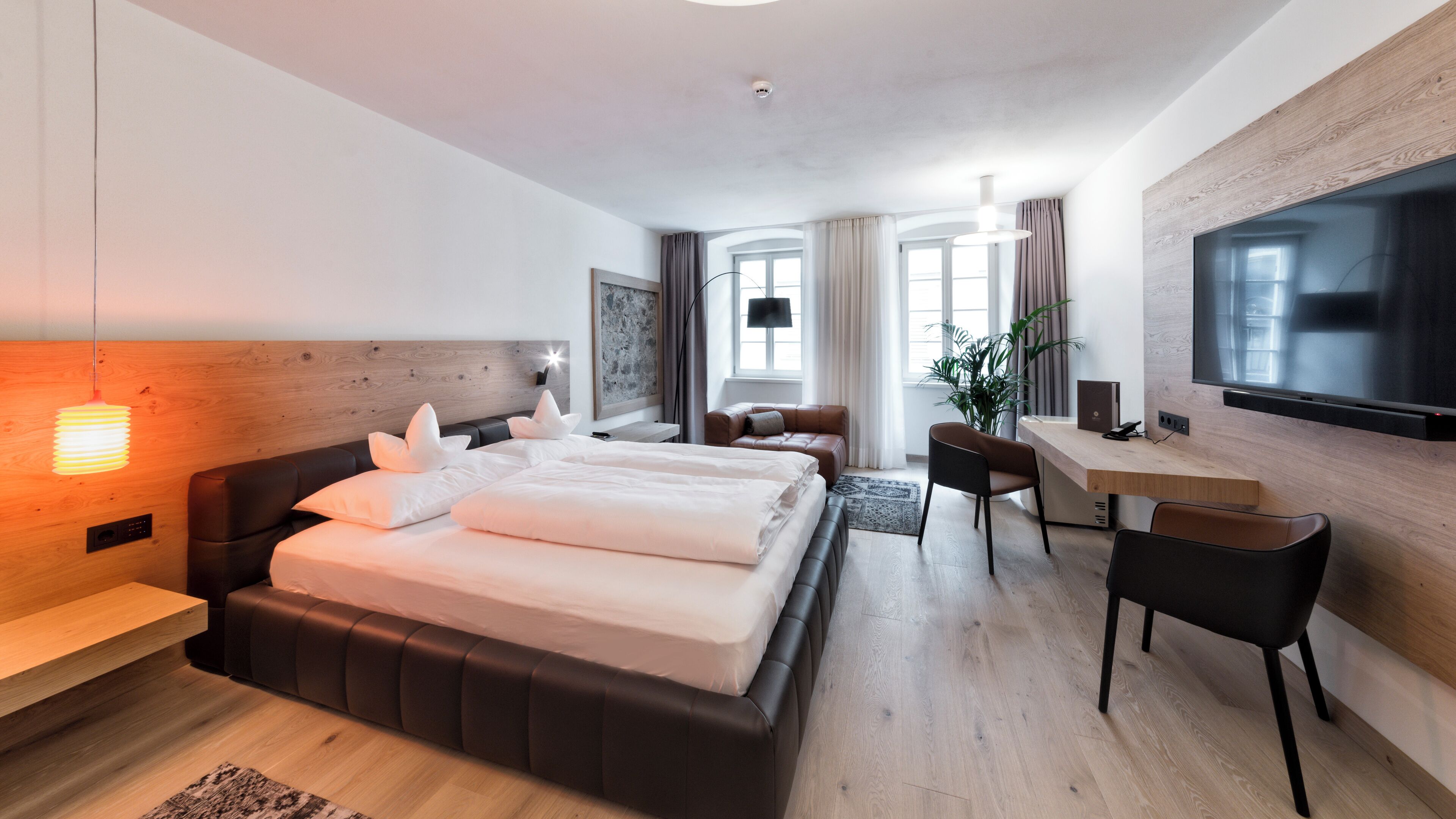 Habitació d'hotel moderna amb un llit gran, una taula de treball, una cadira i un televisor penjat a la paret.