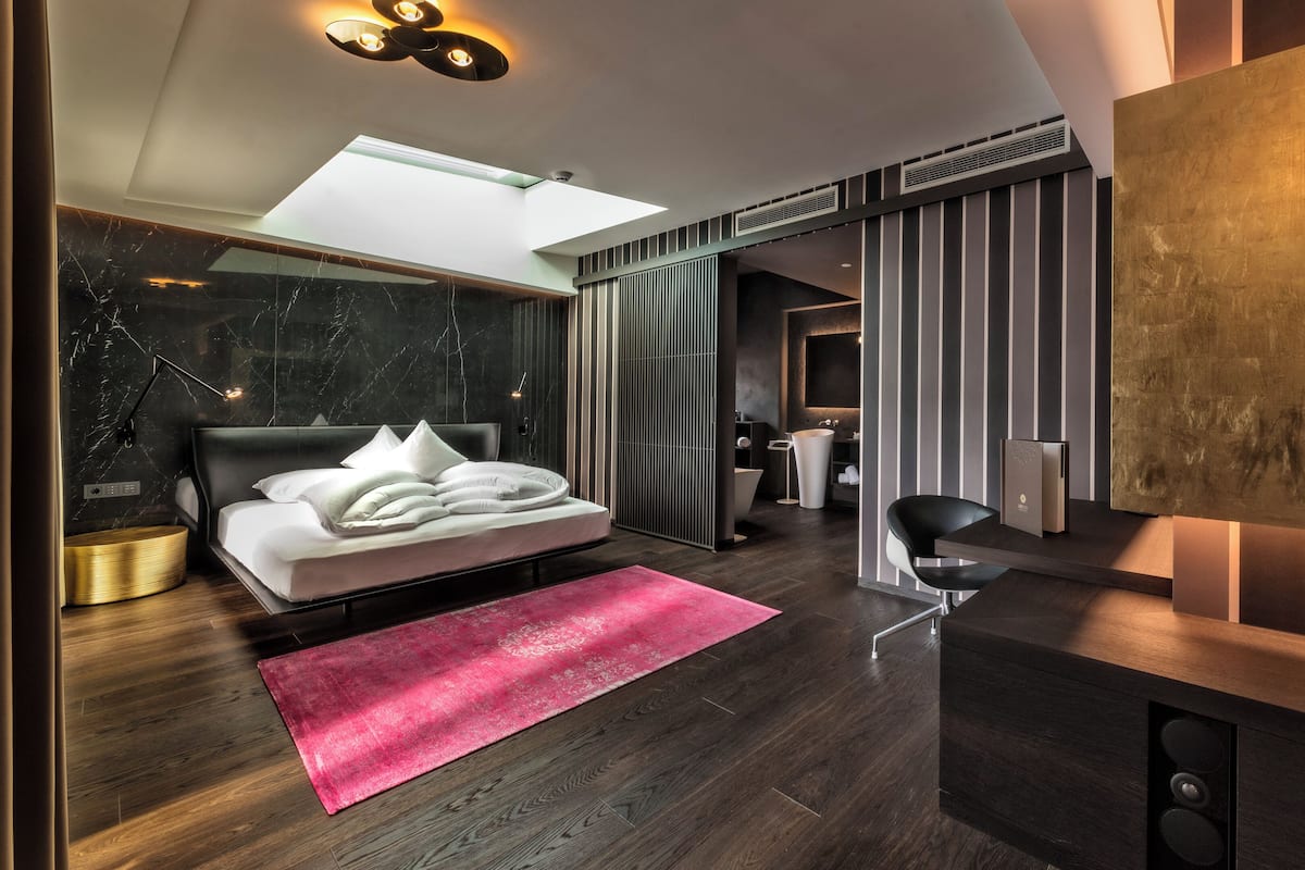 A modern bedroom with a bed, a desk, and a TV.