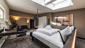 Una habitación de hotel moderna con cama, escritorio, silla y un ventanal grande.