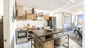 A modern kitchen with built-in appliances, a central island, and a dining area with a view.