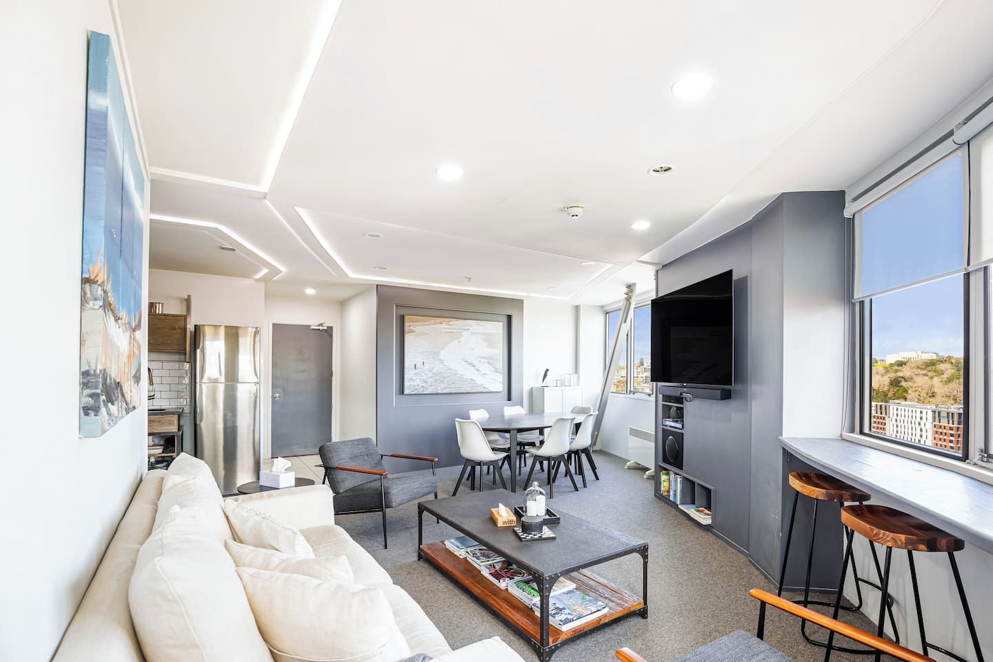 A modern living room with a sofa, coffee table, and a dining area with chairs.