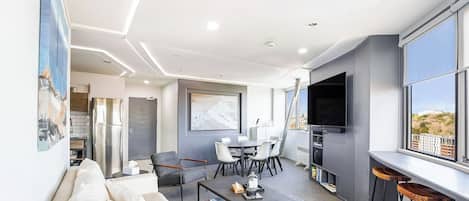 A modern living room with a sofa, coffee table, and a dining area with chairs.