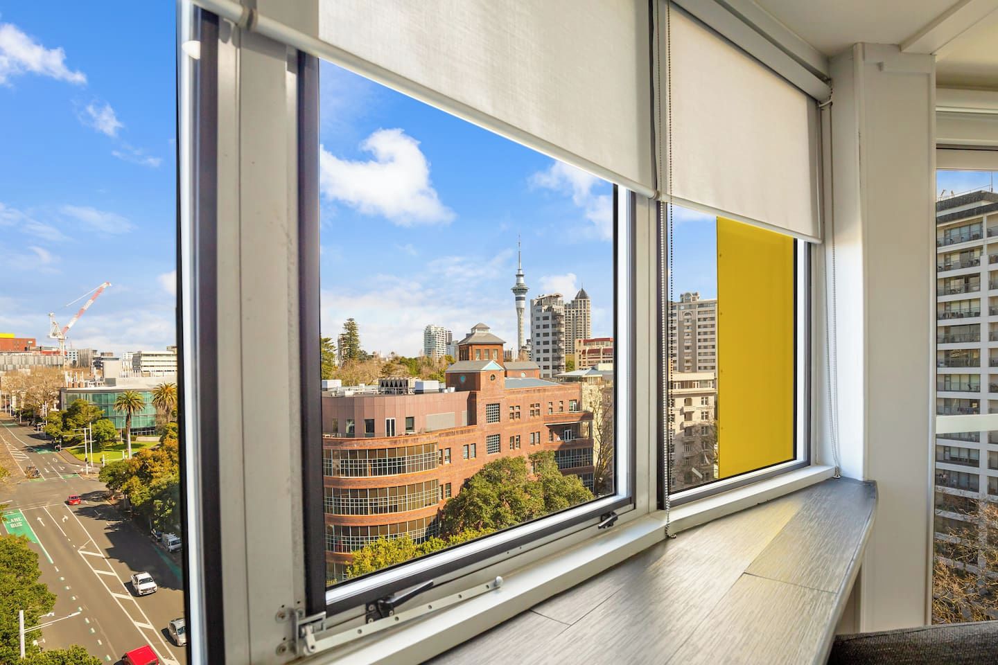 A window with a view of a cityscape, including a prominent tower and various buildings.