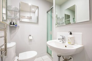 Un baño moderno con un lavamanos blanco, inodoro y cabina de ducha de vidrio.
