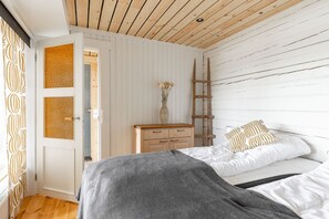 A bedroom with a bed, a dresser, a ladder, and a door leading to another room. - Cozy lodge surrounded by lake (Petäjävesi)