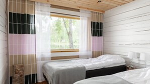 Een kamer met twee bedden, een raam met gordijnen, een houten plafond en een nachtkastje met lampen.