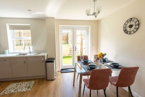 Una cocina moderna con comedor, un reloj en la pared y vistas a través del ventanal.