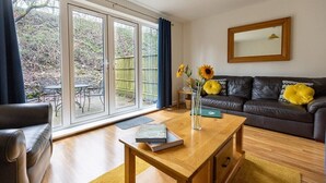 A modern living room with a leather sofa, a wooden coffee table, and a bookshelf. - 4 Bed Property on the Edge of the National Park (Derbyshire)