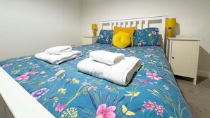 A neatly made bed with floral bedding, two pillows, and two bedside lamps. - 4 Bed Property on the Edge of the National Park (Derbyshire)