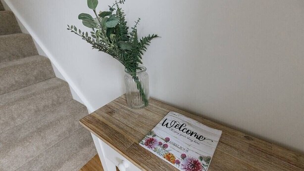 A wooden reception desk with a welcome sign and a vase of greenery. - 4 Bed Property on the Edge of the National Park (Derbyshire)