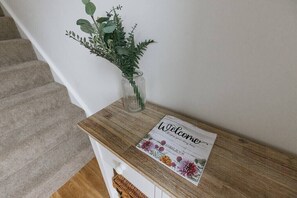 A wooden reception desk with a welcome sign and a vase of greenery.