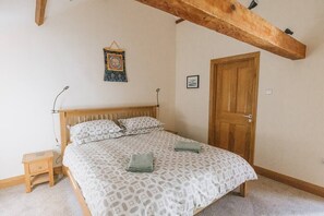 Ein Schlafzimmer mit einem hölzernen Bett, einem kleinen Nachttisch, einer Holztür und einem Wandteppich.