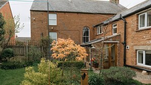 A brick house with a garden, a fire hydrant, and a wooden door. - Converted Barn near Lake District National Park (Carlisle)