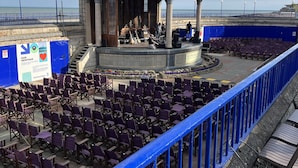 A gazebo-style stage with musicians, surrounded by rows of purple chairs, overlooking a beach. - Perfect Location Near Beach, Shops and Restaurants (Eastbourne)