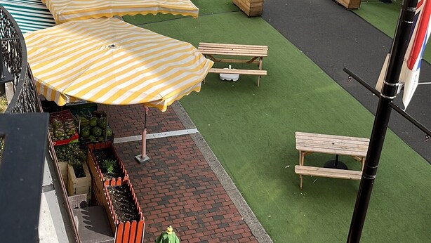 A public square with green artificial turf, wooden benches, and striped umbrellas. - Perfect Location Near Beach, Shops and Restaurants (Eastbourne)