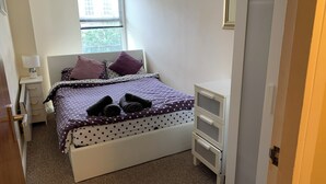 A bedroom with a bed, a nightstand, a dresser, and a window. - Perfect Location Near Beach, Shops and Restaurants (Eastbourne)