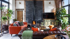 Una sala de estar acogedora con chimenea, sofá de cuero y televisor.