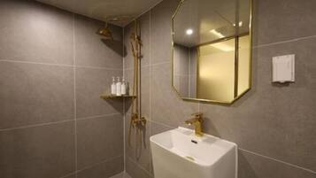 Un baño moderno con un espejo grande, un lavamanos blanco y una zona de ducha.