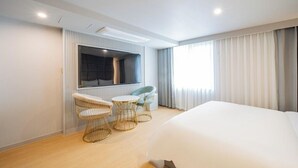 A modern hotel room with a large bed, a seating area with two chairs and a small table, a TV mounted on the wall, and a large window with curtains. - Denbastar Hotel-Kyungnam University Branch (Changwon)