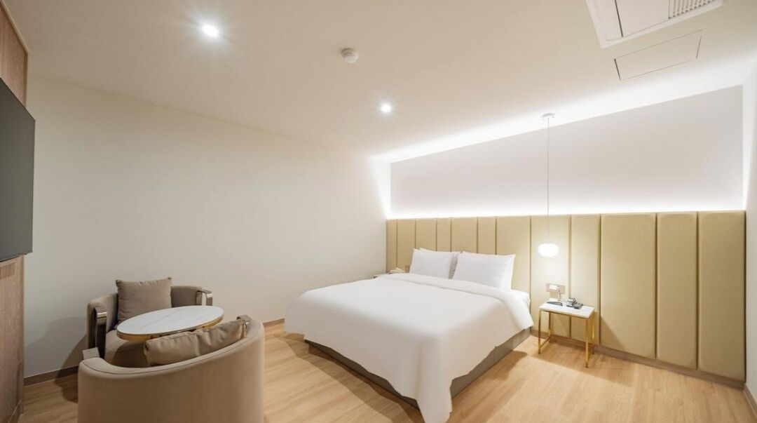 Una habitación de hotel moderna con una cama, una pequeña mesa redonda y una silla.