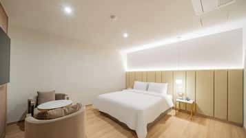 Una habitación de hotel moderna con una cama, una pequeña mesa redonda y una silla.