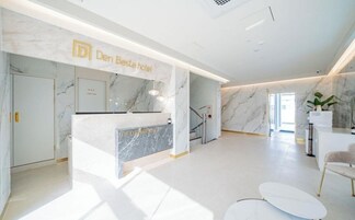 Un área de recepción de hotel moderna, con un mostrador de mármol, una escalera y una zona de estar.