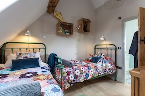 Une chambre mansardée chaleureuse avec deux lits superposés, une tête de lit en bois et un plafond en pente.