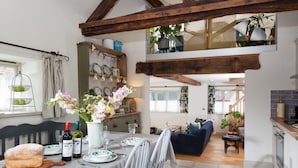 Un coin repas avec une table dressée pour quatre personnes, un banc en bois et une miche de pain posée sur une planche à découper.