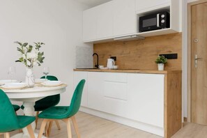 Cocina pequeña con armarios blancos, encimera de madera y microondas.