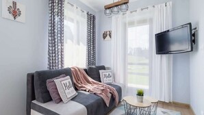 A modern living room with a grey sofa, a small round table, and a mounted TV.