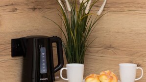 Eine Küchenarbeitsplatte mit einer schwarzen Kaffeemaschine, einer weißen Tasse, einem Tablett mit Gebäck und einem Blumentopf.