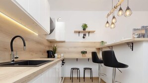 Eine moderne Küche mit einer Holzarbeitsplatte, schwarzen Barhocker und Pendelleuchten.