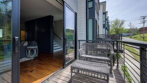 A modern house with a wooden deck, a staircase leading to an interior, and a balcony with wicker furniture. - Modern Townhome w/ Game Room + 10min to Downtown! (Nashville)