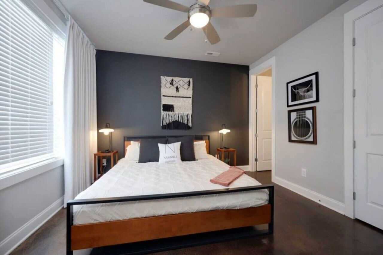 Een slaapkamer met een bed, plafondventilator, wanddecoratie en een deur.