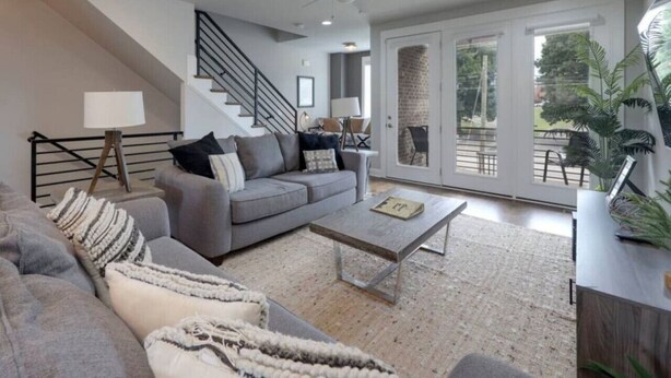 A modern living room with a grey sofa, a coffee table, and a staircase leading to a balcony. - Private Deck, Views, & Mini-Golf! 10 to Downtown! (Nashville)