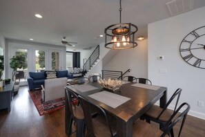 Un espace repas moderne avec une table en bois, des chaises noires et une grande horloge murale.