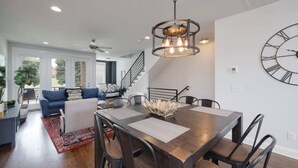 A modern dining area with a wooden table, black chairs, and a decorative centerpiece.