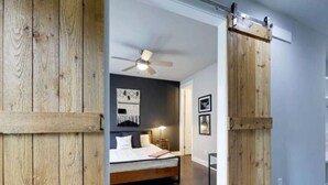 A bedroom with a bed, a ceiling fan, and wooden walls.