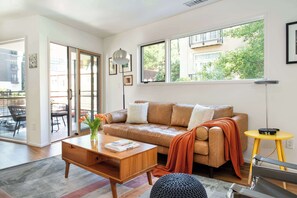 A modern living room with a leather sofa, a wooden coffee table, and a yellow side table.