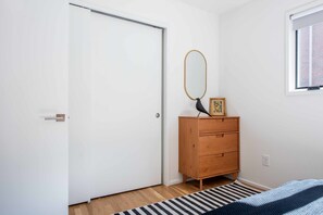 Ein Schlafzimmer mit einem Holzkasten, einem Spiegel und einem Bett mit einem Streifen Teppich.